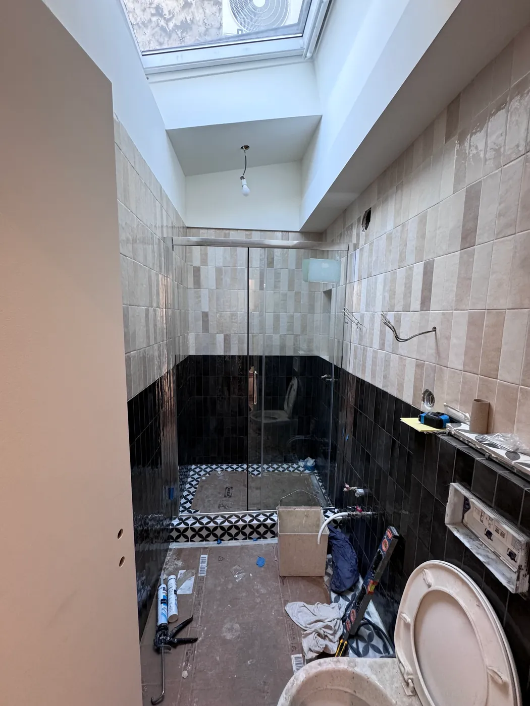 Douche à l'italienne en cours de finition, sol en carreaux de ciment noir et blanc