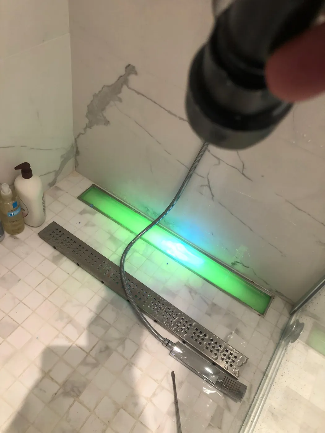 Caniveau de douche grille déposée, traceur fluorescent vert révélé à la lampe UV