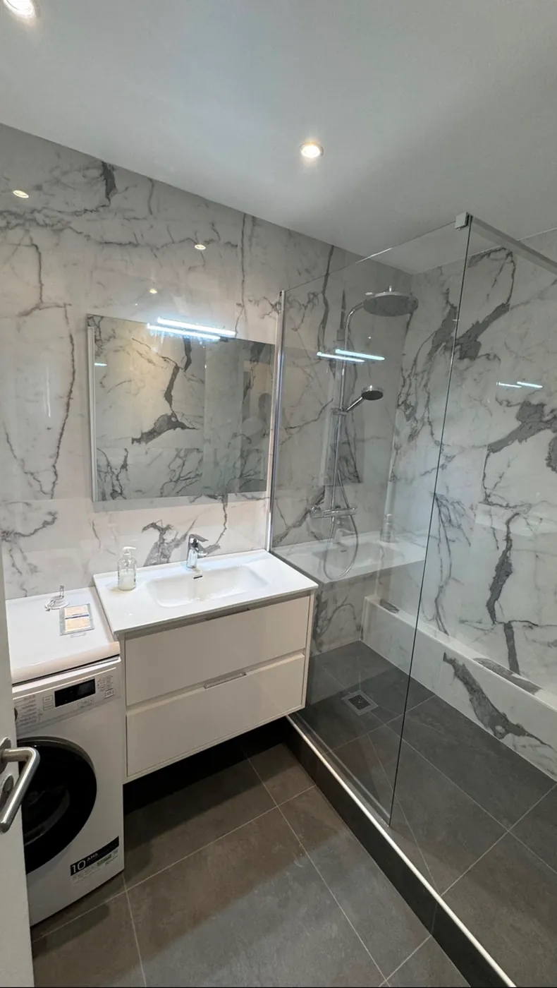 Salle de bain en marbre blanc veiné avec meuble vasque et douche vitrée